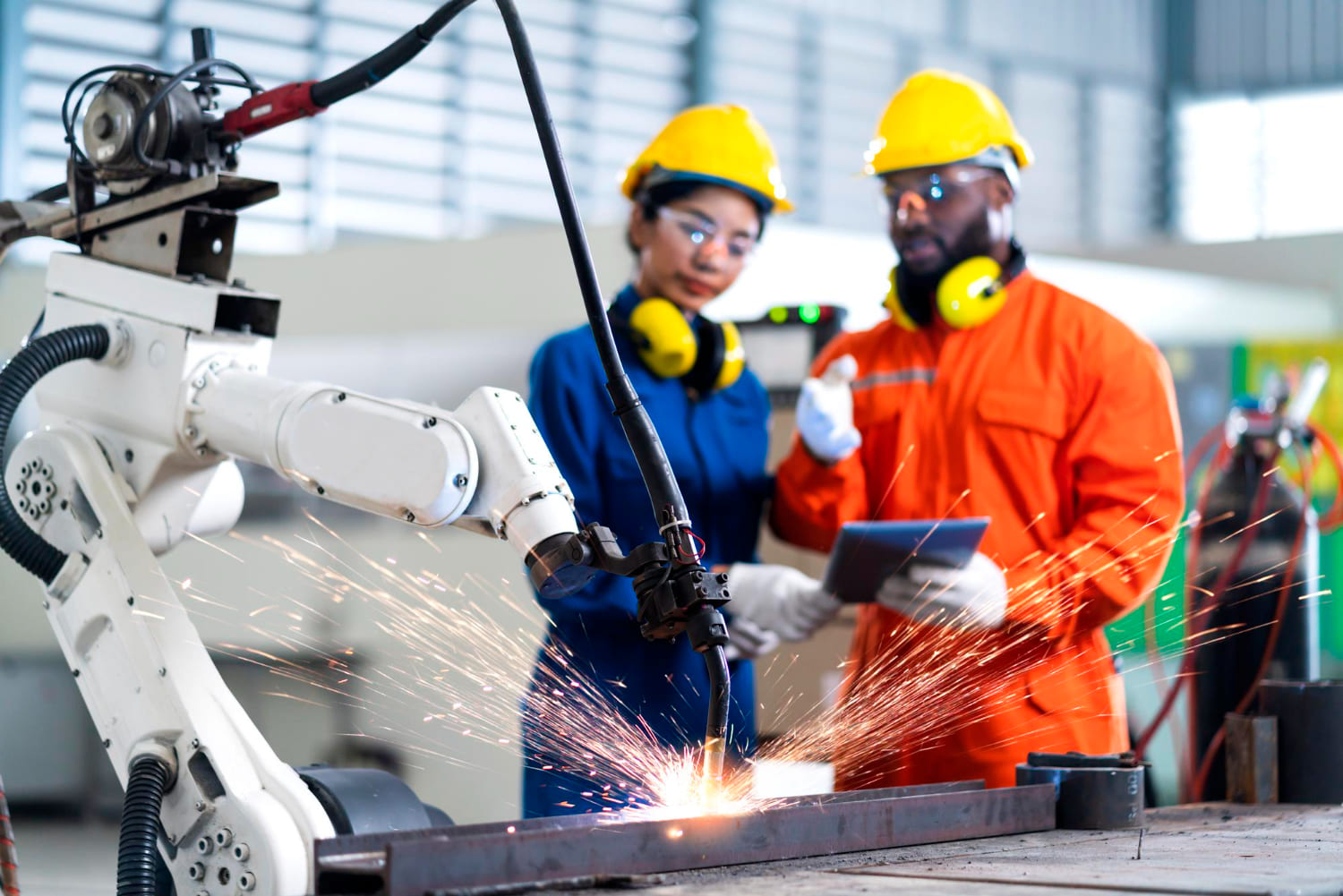 a man, a woman and robot in a manufacturing room